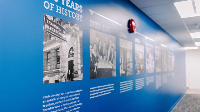 Yorkville University - Blue wall with images and text that showcases the 100 years of history of the university 