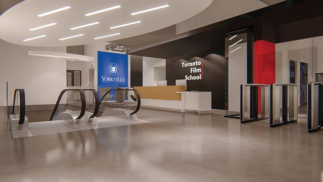 view of inside the shared campus building of Yorkville University and Toronto Film School - showing wall signage for both institutions, and escalator, and a reception desk area