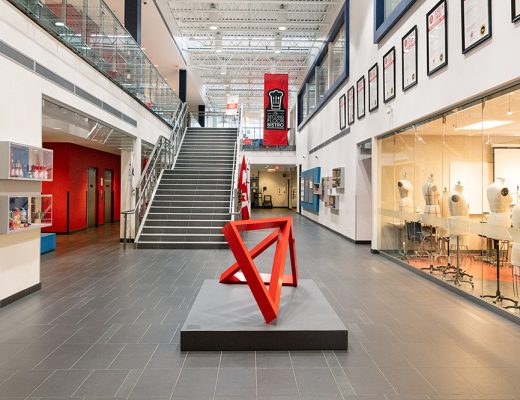 The interior of the LaSalle College Vancouver building, showing a red sculpture in the hallway and a brightly lit classroom containing mannequins for design classes.