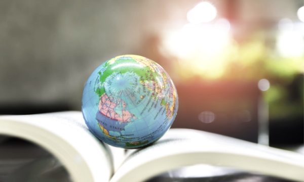 A small world globe placed atop the pages of an open book.