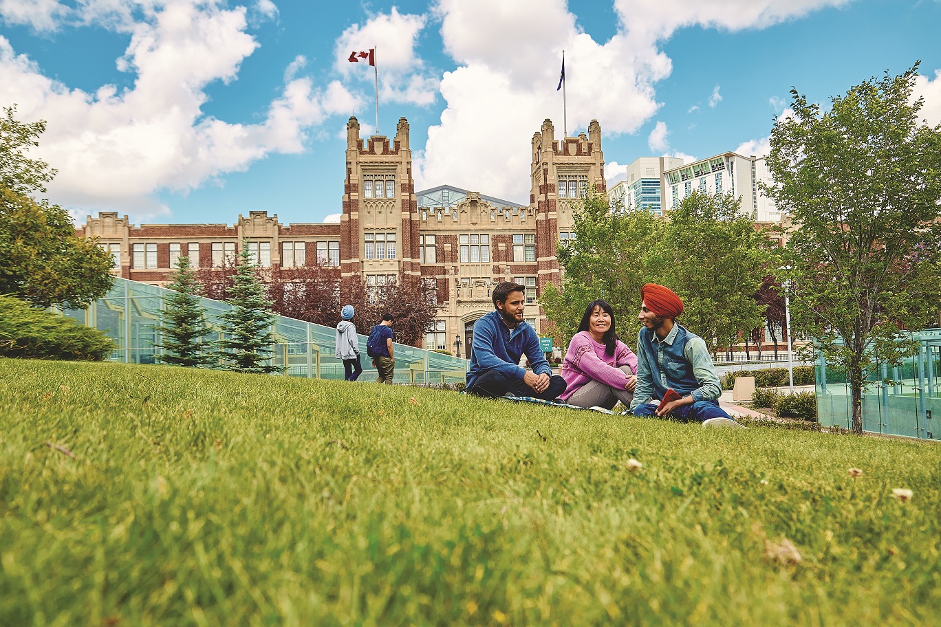 A group of students sitting on the grass outside of Heritage Hall at Southern Alberta Institute of Technology, one of ILSC Language Schools' University Pathway Partners in Canada.