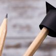 Three pencils in a pencil holder with a tiny graduate hat on one of the pencils.